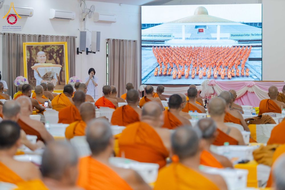 พระภิกษุสงฆ์นั่งฟังการบรรยายในห้องประชุม โดยมีจอภาพขนาดใหญ่แสดงภาพพระภิกษุสงฆ์จำนวนมากหน้ามหาธรรมกายเจดีย์