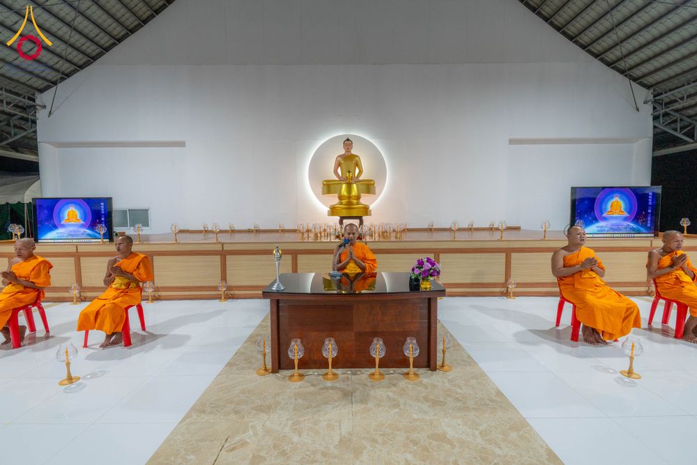 พระภิกษุสงฆ์นั่งสมาธิและนำสวดมนต์ในอาคารปฏิบัติธรรมที่มีพระพุทธรูปเป็นประธาน