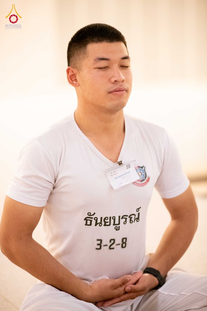 นักเรียนนายสิบตำรวจชายสวมเสื้อยืดสีขาวกำลังนั่งหลับตาทำสมาธิ