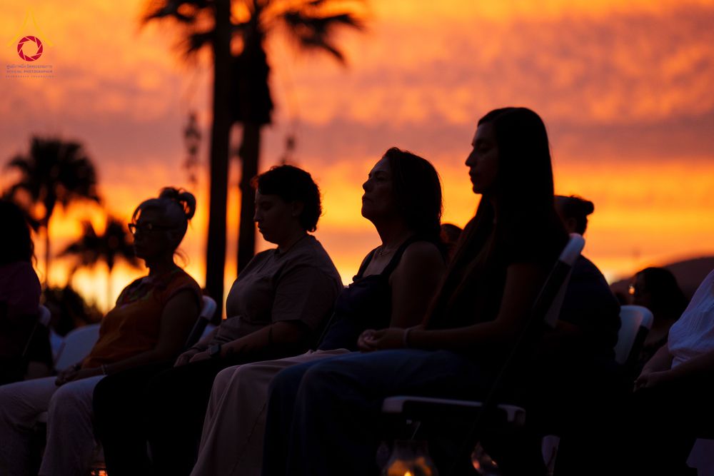 กลุ่มคนนั่งสมาธิในลักษณะภาพเงาดำท่ามกลางแสงสีส้มของท้องฟ้ายามเย็น