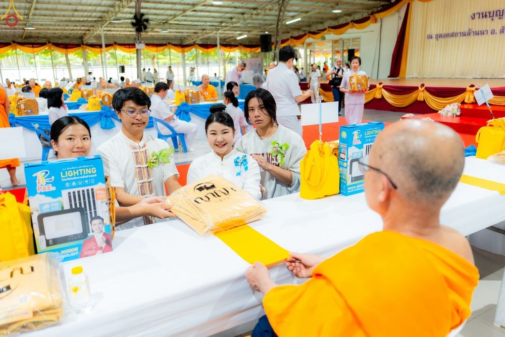 กลุ่มคนในชุดสีขาวกำลังถวายของแด่พระภิกษุสงฆ์ในงานบุญ