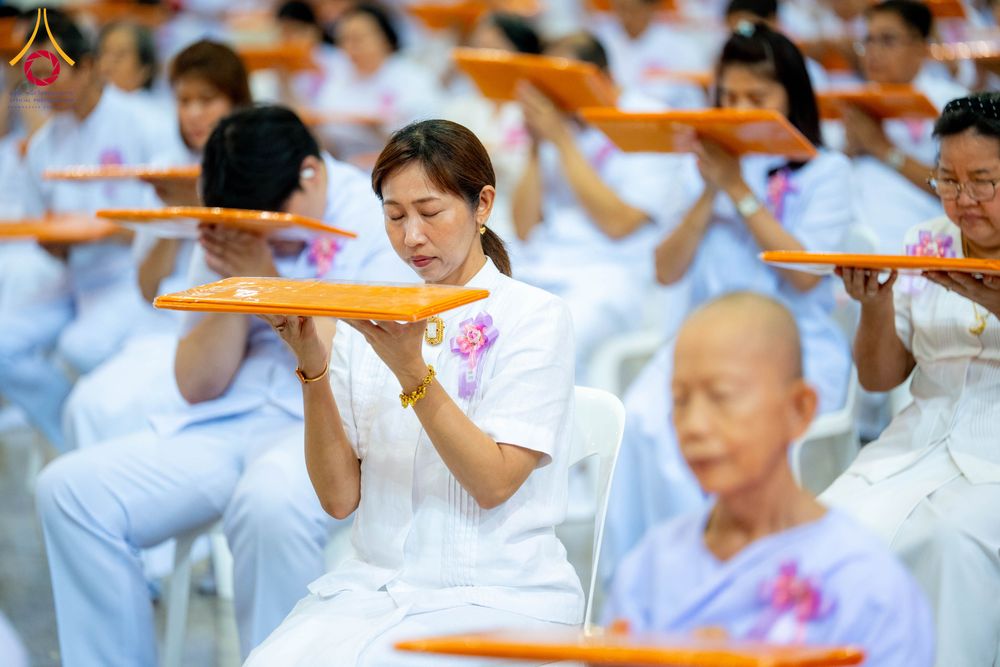 กลุ่มคนสวมชุดขาวถือพานสีส้มประกอบพิธีทางศาสนาภายในอาคาร