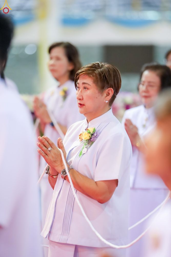 หญิงวัยกลางคนสวมชุดสีขาวพนมมือในพิธีทางศาสนา