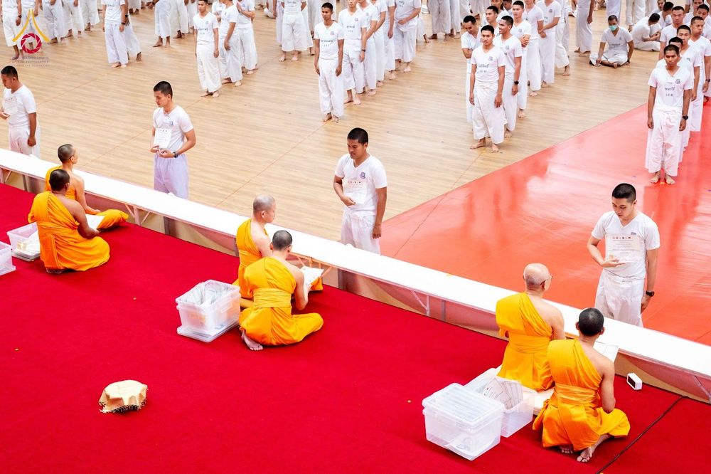นักเรียนนายสิบตำรวจในชุดขาวกำลังรับมอบเกียรติบัตรจากพระสงฆ์ในพิธีปิดโครงการบรรพชา