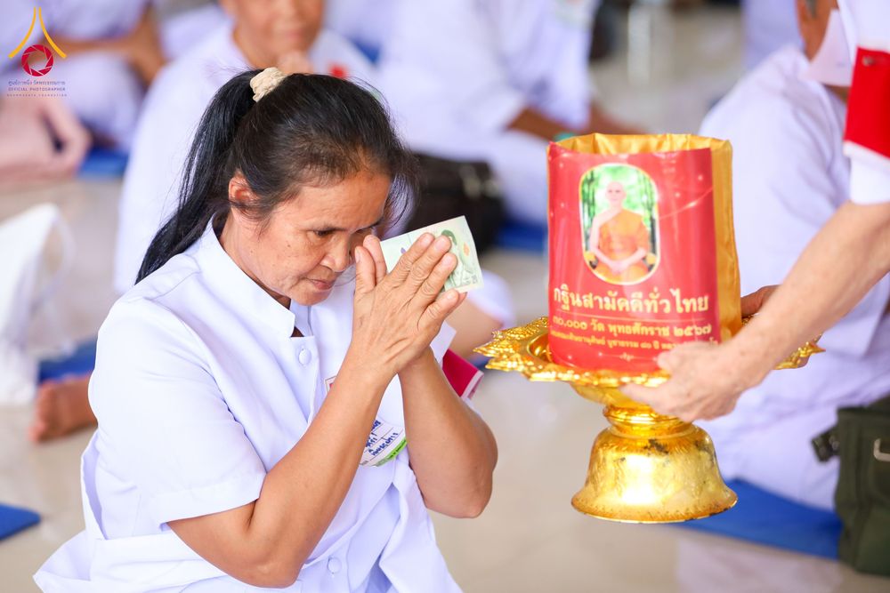 อุบาสิกาแก้วสวมชุดขาวพนมมือถือเงินทำบุญหน้าพานวางกล่องรับบริจาคกฐินสามัคคี