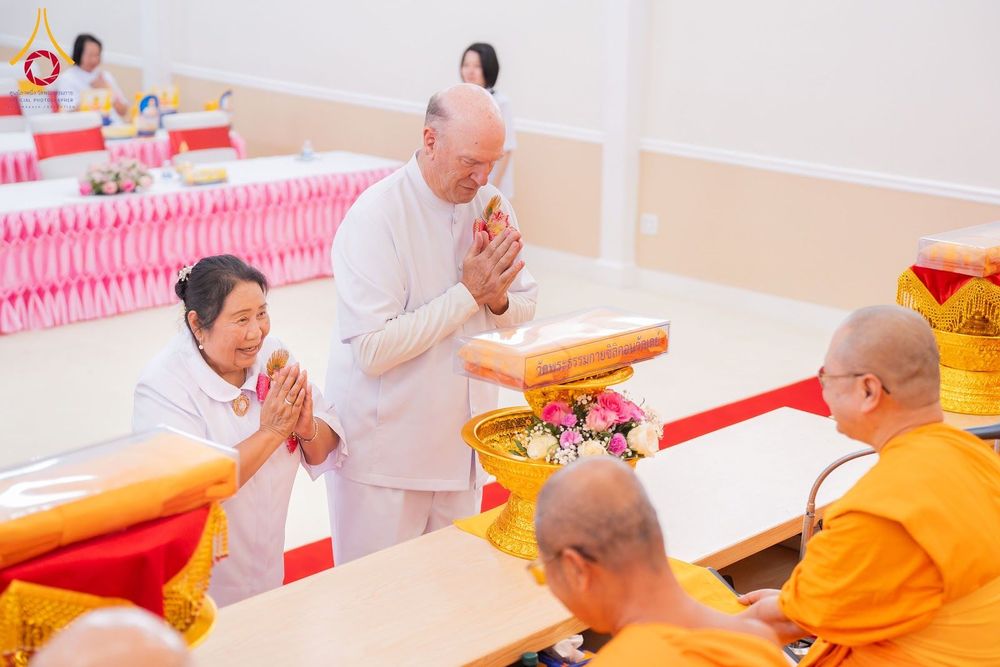 พุทธศาสนิกชนชายหญิงในชุดขาวกำลังประนมมือไหว้พระภิกษุสงฆ์ในพิธีทางศาสนา