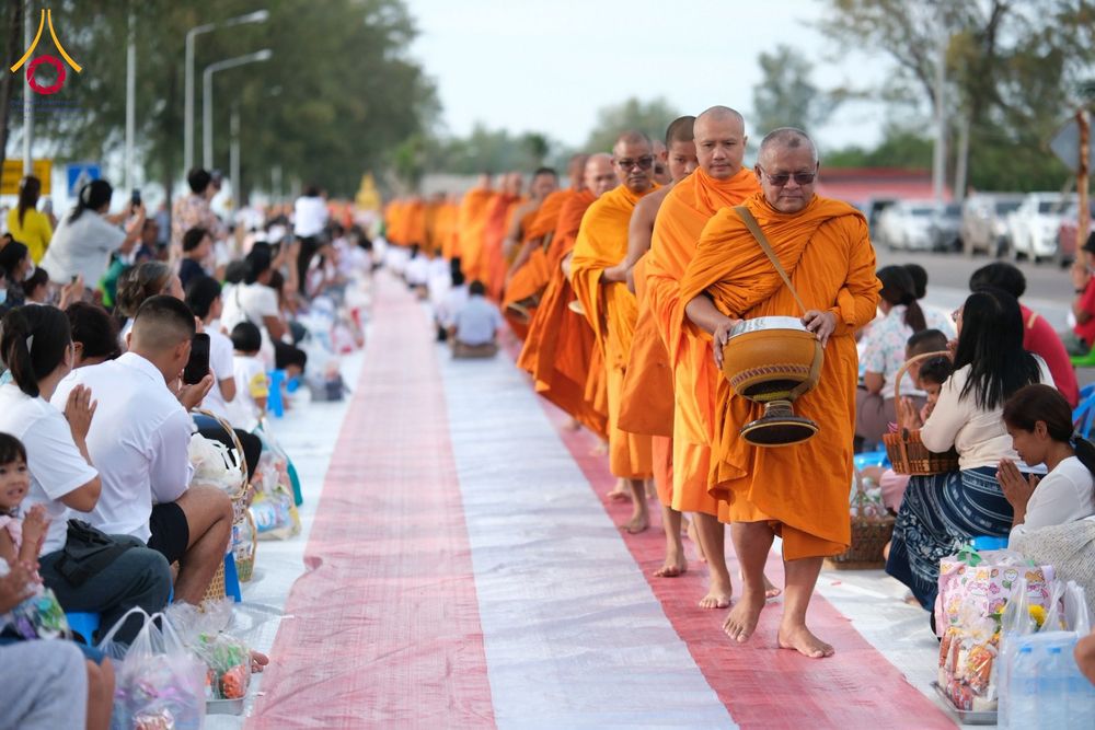 แถวพระสงฆ์เดินรับบิณฑบาตจากประชาชนที่นั่งรออยู่ริมชายหาด