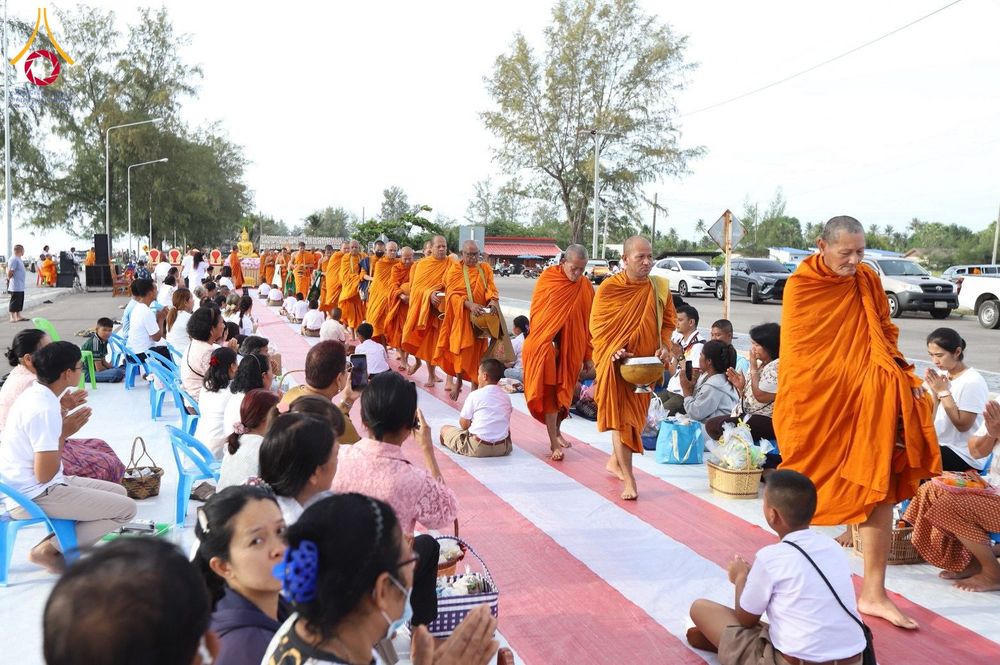 พระสงฆ์เดินรับบิณฑบาตจากประชาชนที่นั่งรอใส่บาตรริมชายหาด