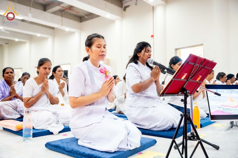 กลุ่มพุทธศาสนิกชนสวมชุดสีขาวนั่งพนมมือสวดมนต์ภายในอาคาร