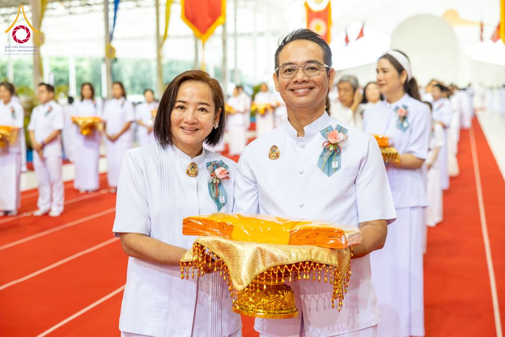 ชายและหญิงสวมชุดสีขาวถือพานผ้าไตรจีวรในพิธีทางศาสนา