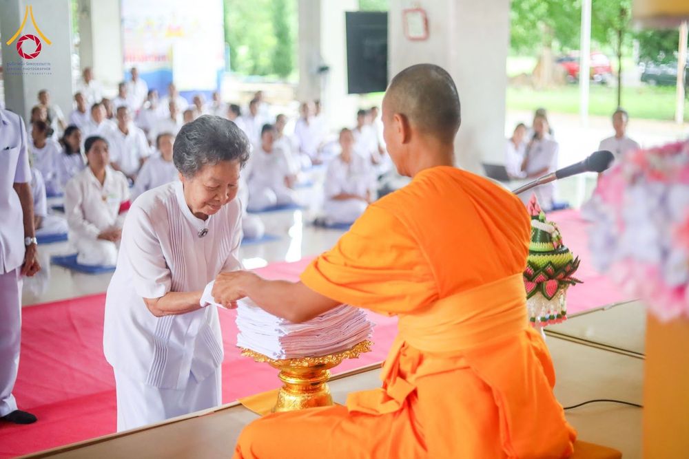 อุบาสิกาแก้วกำลังถวายผ้าไตรแด่พระภิกษุสงฆ์ในพิธีทางศาสนา