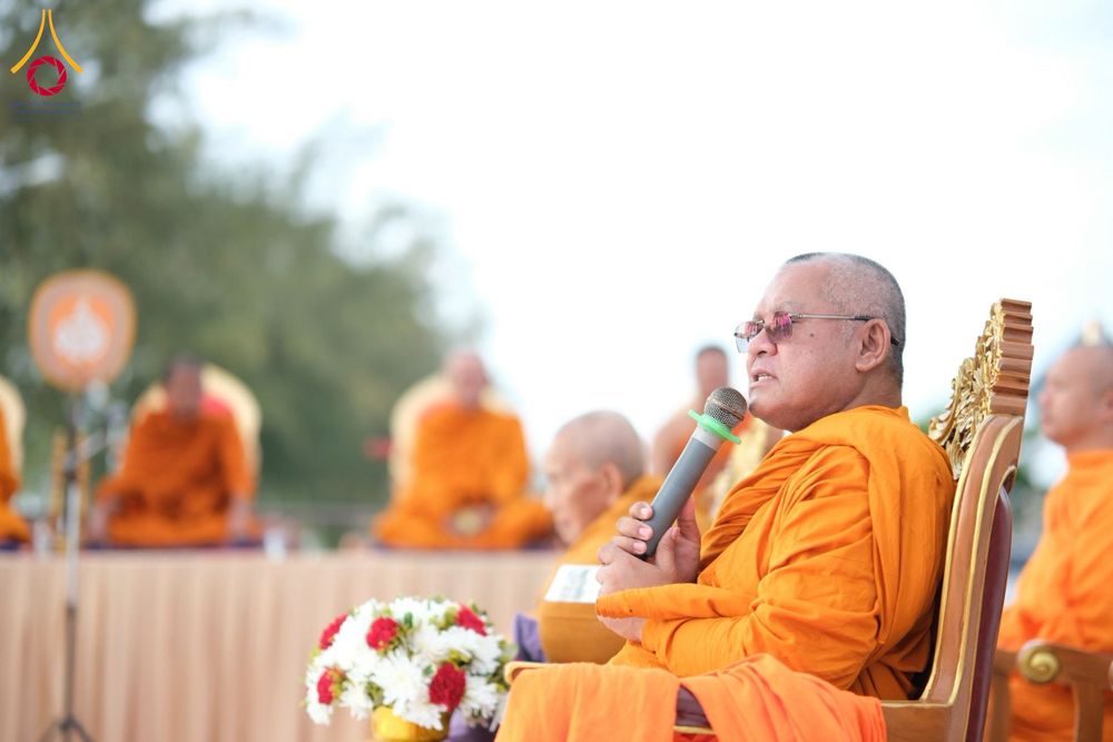 พระสงฆ์ถือไมโครโฟนกล่าวธรรมบรรยายบนเวทีในพิธีตักบาตร