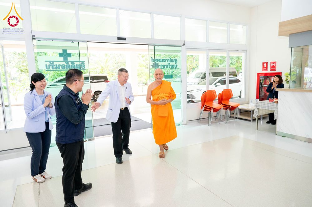 พระภิกษุสงฆ์เดินเข้าสู่อาคารศูนย์การแพทย์บุญรักษาโดยมีเจ้าหน้าที่ยืนต้อนรับ