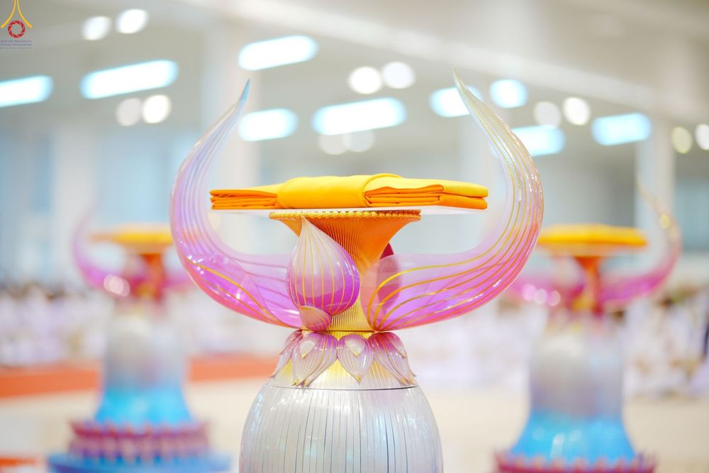 พานวางผ้าไตรจีวรสีเหลืองทองบนพานรูปดอกบัวสีเงินและสีชมพู