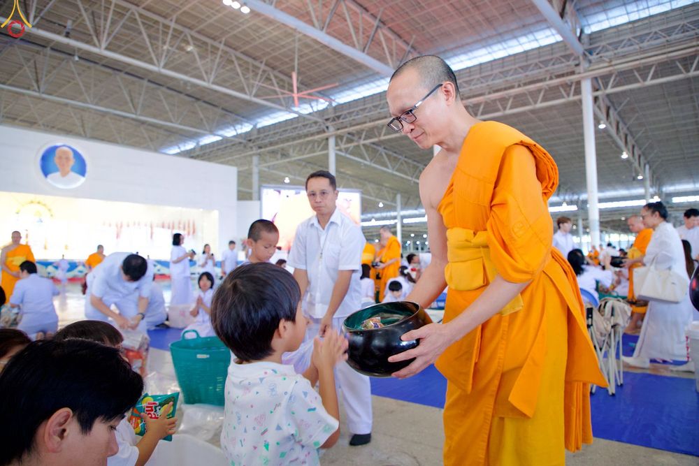 พระภิกษุสงฆ์รับบาตรจากเด็กชายในพิธีตักบาตรท่ามกลางพุทธศาสนิกชนที่มาร่วมงาน