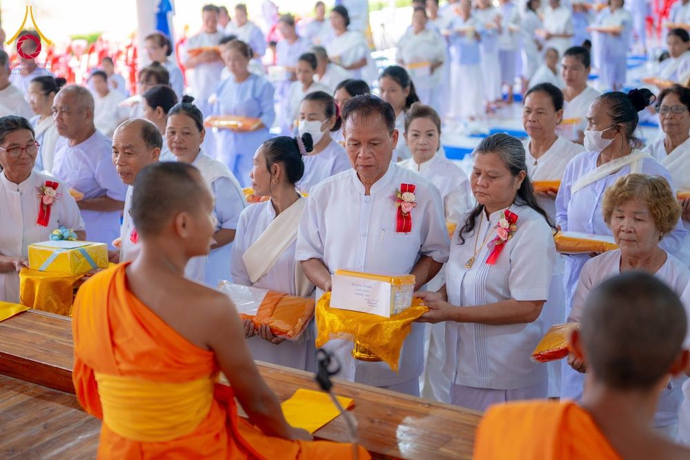 กลุ่มอุบาสกอุบาสิกาชุดขาวกำลังถวายสังฆทานแด่พระภิกษุสงฆ์ในโครงการอบรม