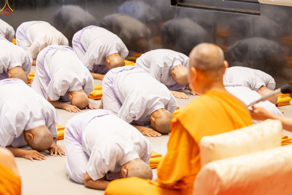ผู้เข้าร่วมโครงการอุปสมบทหมู่ในชุดขาวกราบลงกับพื้นต่อหน้าพระภิกษุสงฆ์ภายในโบสถ์