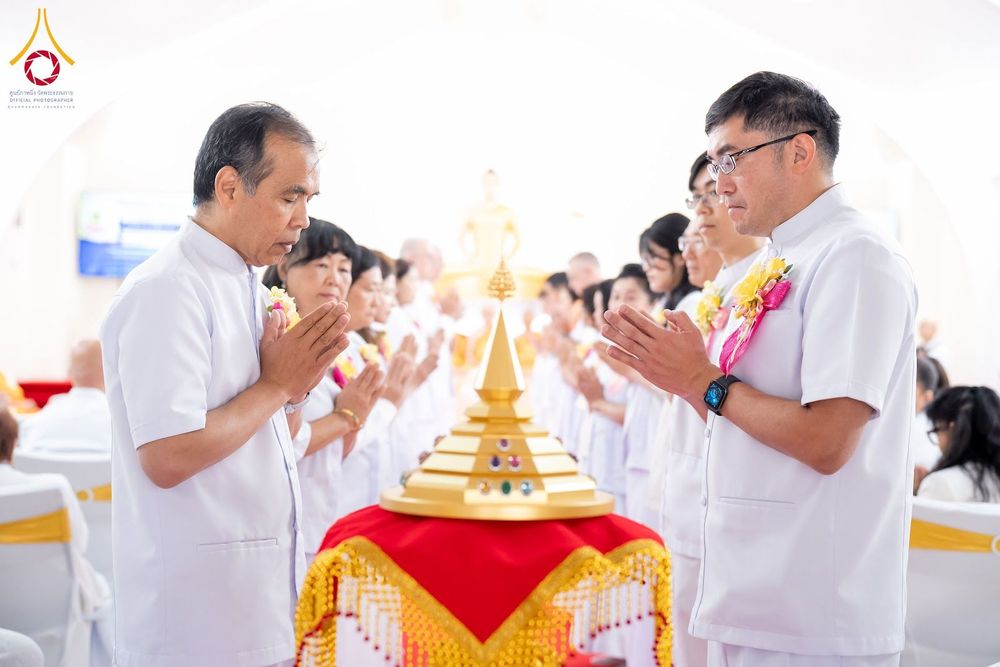 กลุ่มคนสวมชุดขาวพนมมือไหว้พระบรมสารีริกธาตุที่วางอยู่บนพานทองในพิธีทางศาสนา
