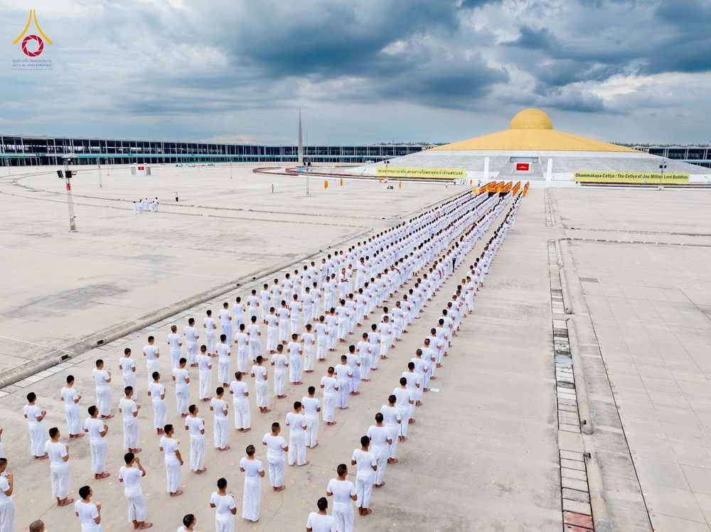 กลุ่มคนจำนวนมากสวมชุดขาวเข้าแถวอย่างเป็นระเบียบในลานกว้างหน้าอาคารทรงโดมสีทอง