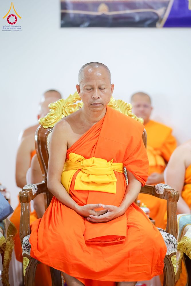 พระภิกษุสงฆ์นั่งสมาธิบนเก้าอี้ไม้แกะสลักสีทองในพิธีทางศาสนา