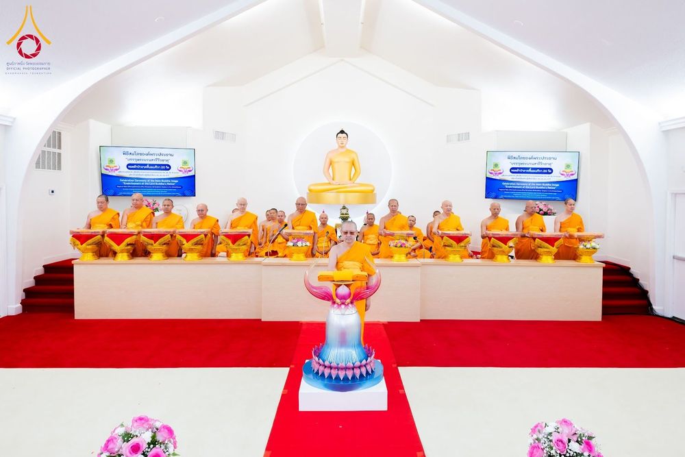 คณะสงฆ์นั่งเรียงแถวบนอาสนะในพิธีทอดผ้าป่าภายในอุโบสถที่มีพระพุทธรูปประดิษฐานอยู่ด้านหลัง