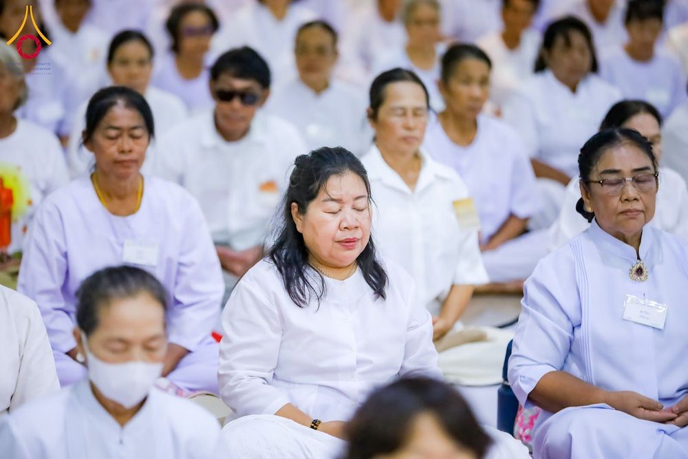กลุ่มผู้เข้าร่วมโครงการปฏิบัติธรรมสวมชุดสีขาวนั่งหลับตาทำสมาธิ