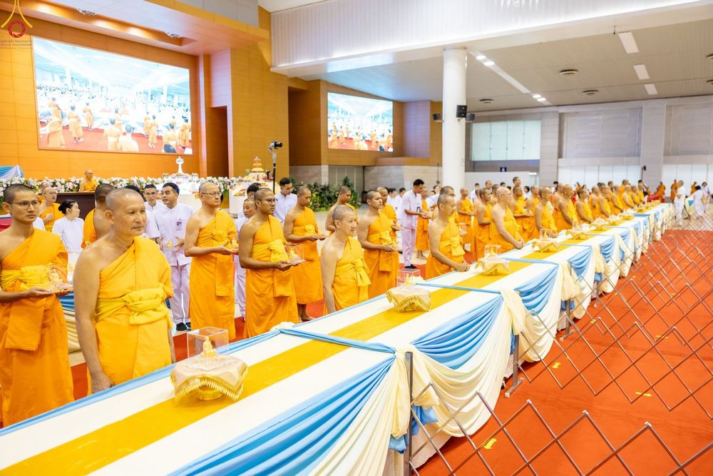 พระภิกษุสงฆ์ยืนเรียงแถวในพิธีมอบพระของขวัญภายในห้องโถงกว้าง