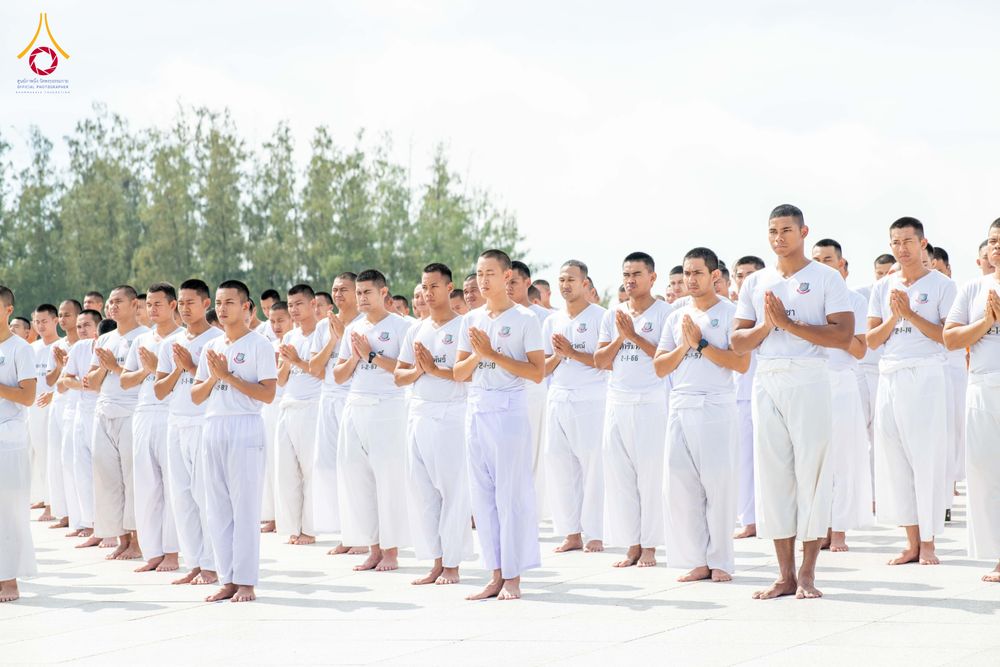 กลุ่มนักเรียนนายสิบตำรวจสวมชุดขาวพนมมือปฏิบัติธรรมยืนเรียงแถวอย่างเป็นระเบียบ