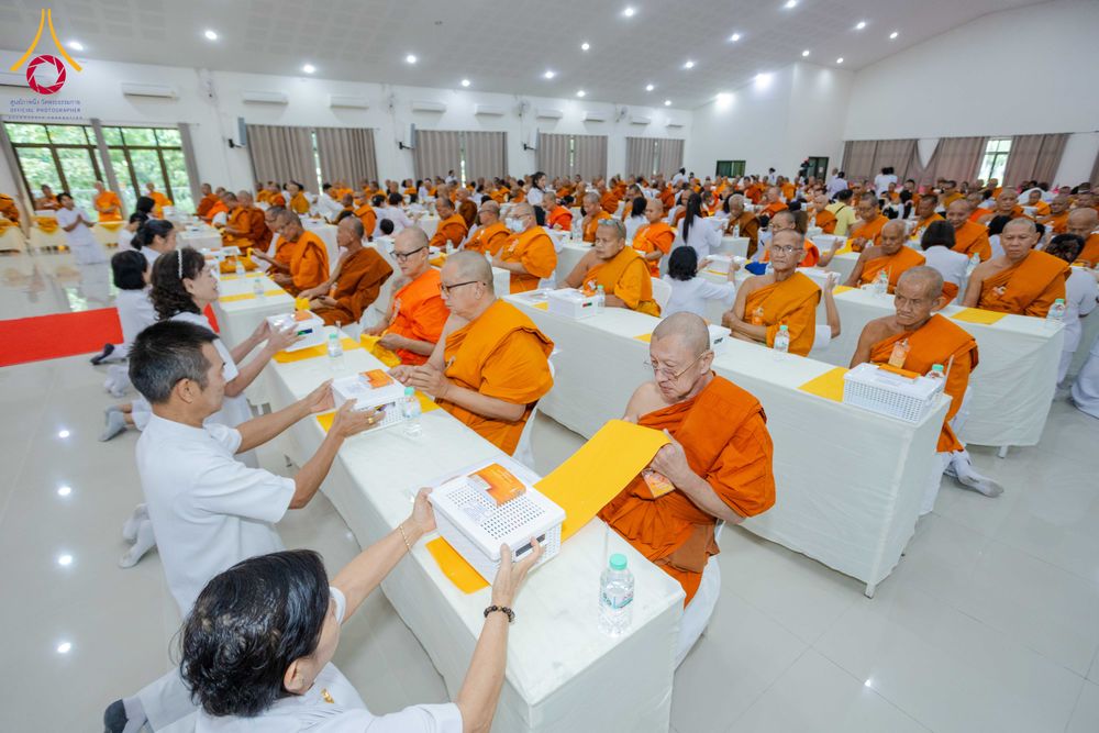 พระภิกษุและพุทธศาสนิกชนร่วมกิจกรรมสัมมนาภายในห้องประชุมขนาดใหญ่ โดยมีอาสาสมัครกำลังแจกจ่ายสิ่งของให้กับพระภิกษุ