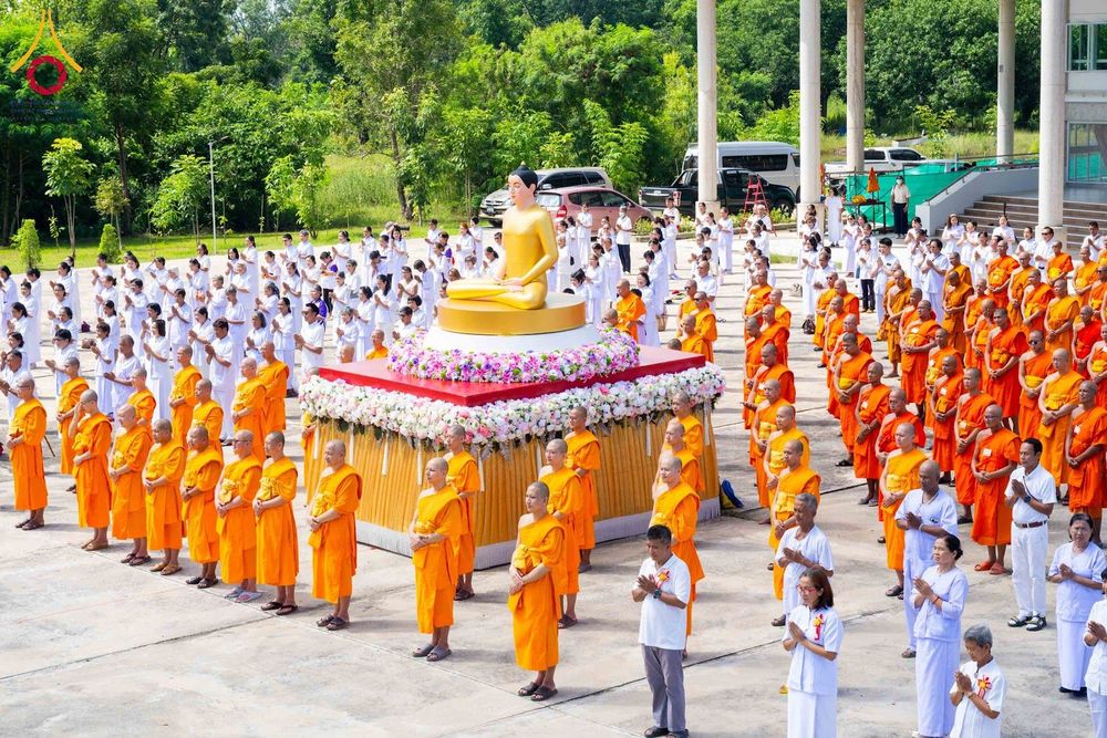พระภิกษุสงฆ์และพุทธศาสนิกชนในชุดขาวร่วมพิธีอัญเชิญพระประธานสีทองประดิษฐานบนฐานประดับดอกไม้