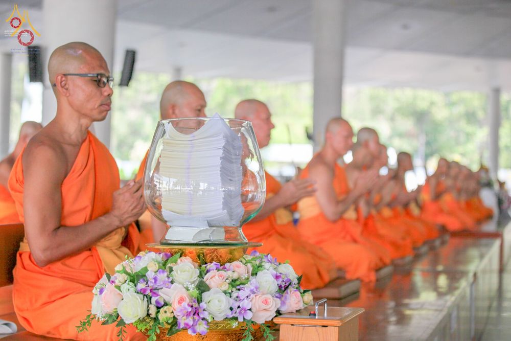 พระภิกษุสงฆ์นั่งสมาธิและประกอบพิธีบุพเปตพลี โดยมีโหลแก้วบรรจุรายชื่อผู้ล่วงลับวางอยู่ด้านหน้า ณ หอฉันคุณยายอาจารย์มหารัตนอุบาสิกาจันทร์ ขนนกยูง