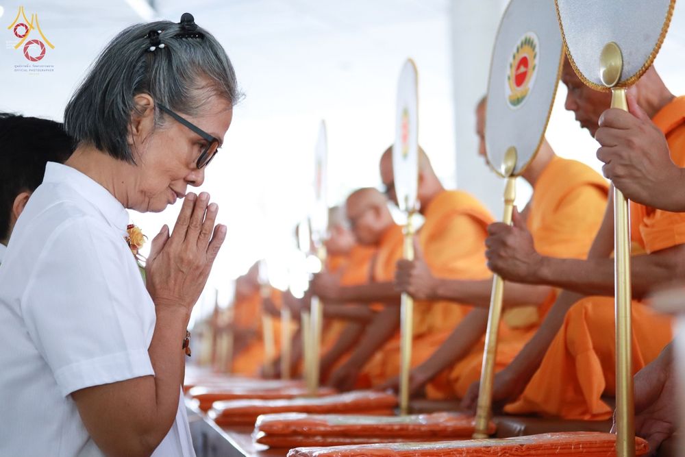 หญิงสูงวัยสวมชุดขาวประนมมือไหว้พระสงฆ์ที่กำลังถือตาลปัตรประกอบพิธีบุพเปตพลี