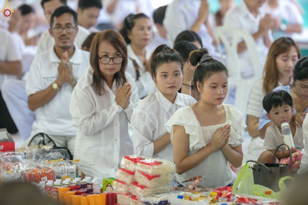 กลุ่มพุทธศาสนิกชนสวมชุดสีขาวพนมมือร่วมพิธีตักบาตรในโครงการยุวธรรมทายาท ณ วัดพระธรรมกาย