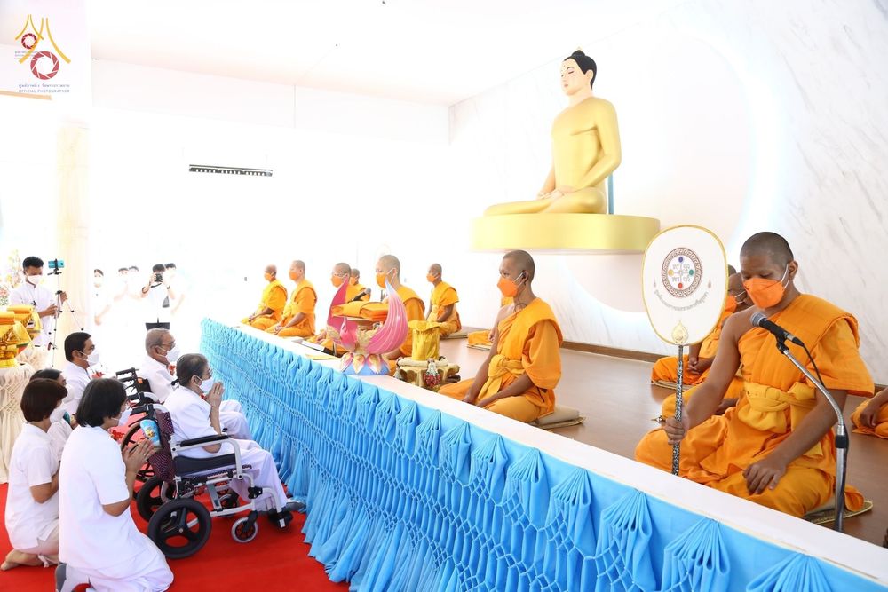 พระสงฆ์และพุทธศาสนิกชนร่วมพิธีทอดกฐินสามัคคีภายในอาคารปฏิบัติธรรมที่มีพระพุทธรูปประดิษฐานอยู่ด้านหลัง