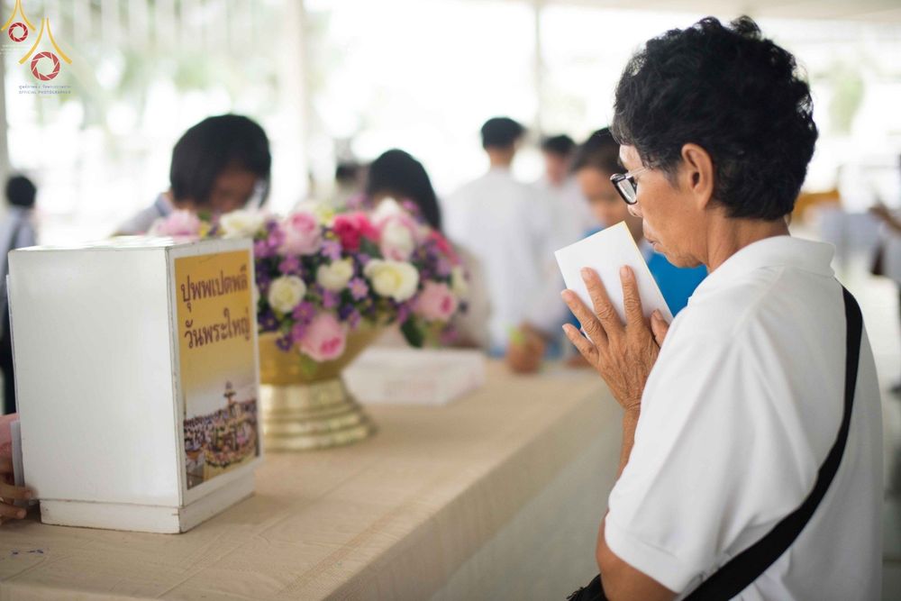 หญิงสูงวัยพนมมือถือซองปัจจัยร่วมทำบุญในพิธีปุพพเปตพลีที่วัดพระธรรมกาย