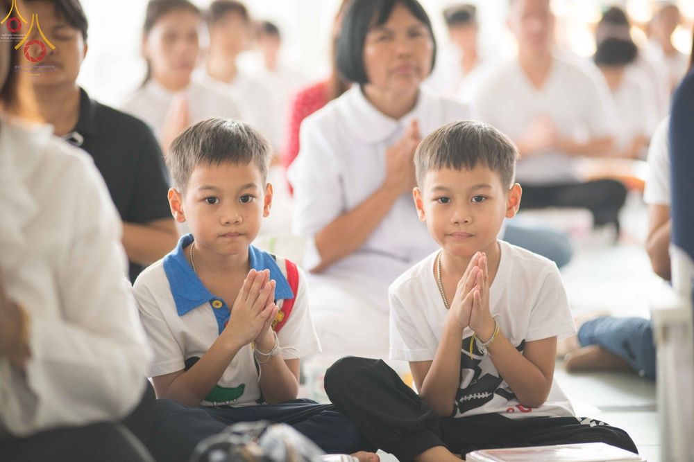 เด็กชายสองคนนั่งพนมมือร่วมพิธีทางศาสนาในหอฉันคุณยายอาจารย์ฯ วัดพระธรรมกาย
