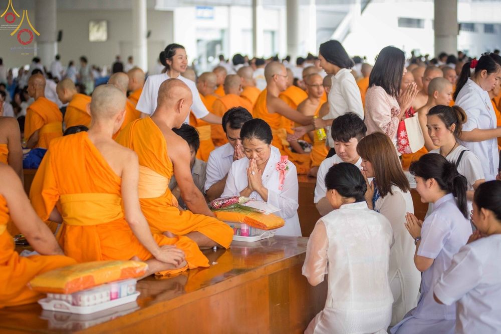 พุทธศาสนิกชนชุดขาวนั่งพนมมือร่วมพิธีปุพพเปตพลีต่อหน้าพระภิกษุสงฆ์ภายในหอฉันคุณยายอาจารย์ฯ วัดพระธรรมกาย