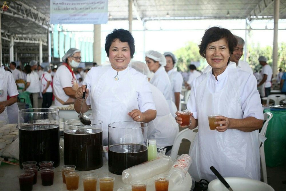 อาสาสมัครหญิงสองท่านกำลังตักและถือแก้วเครื่องดื่มให้บริการในกิจกรรมบุญวันอาทิตย์ต้นเดือน
