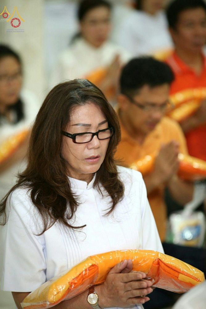 หญิงสวมชุดขาวถือผ้าไตรจีวรในพิธีทอดกฐินสามัคคีที่วัดพุทธจากาตาร์