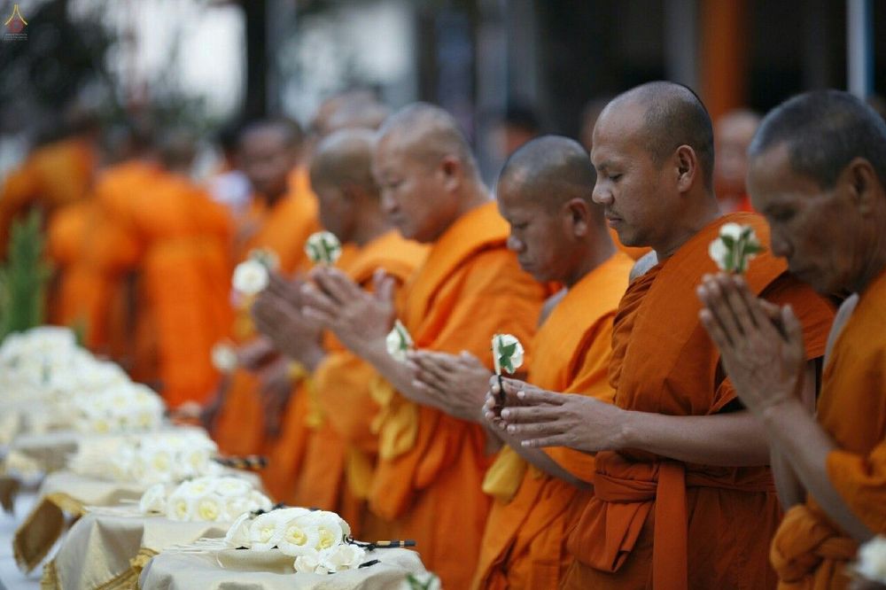 พระภิกษุสงฆ์ยืนพนมมือถือดอกไม้จันทน์ในพิธีถวายดอกไม้จันทน์