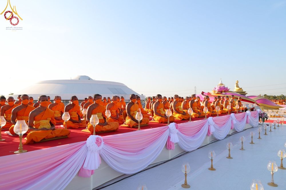 พระภิกษุสงฆ์นั่งสมาธิเรียงแถวบนเวทีเพื่อประกอบพิธีจุดประทีปถวายเป็นพุทธบูชา