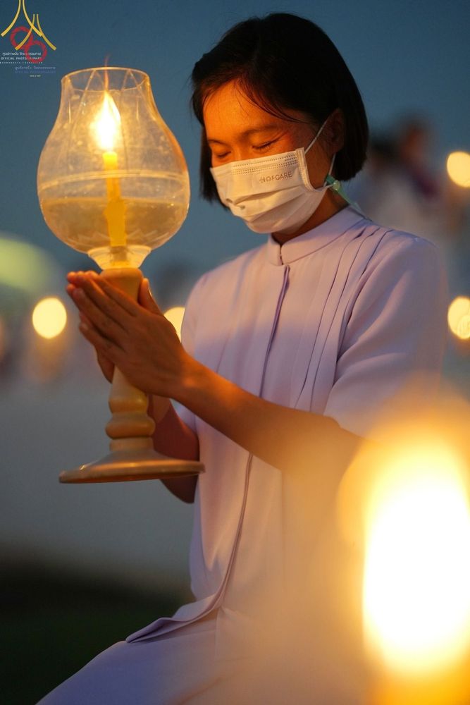 หญิงไทยสวมชุดขาวถือโคมประทีปในพิธีจุดประทีปถวายเป็นพุทธบูชา