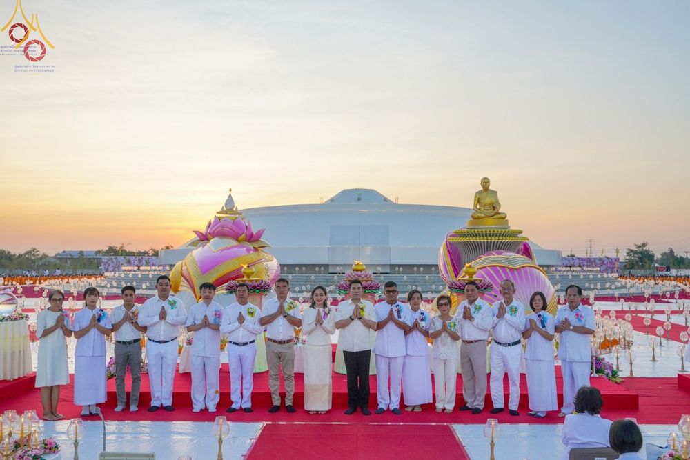 กลุ่มพุทธศาสนิกชนในชุดขาวร่วมถ่ายภาพหน้าอนุสรณ์สถานบางปลาในพิธีจุดประทีป