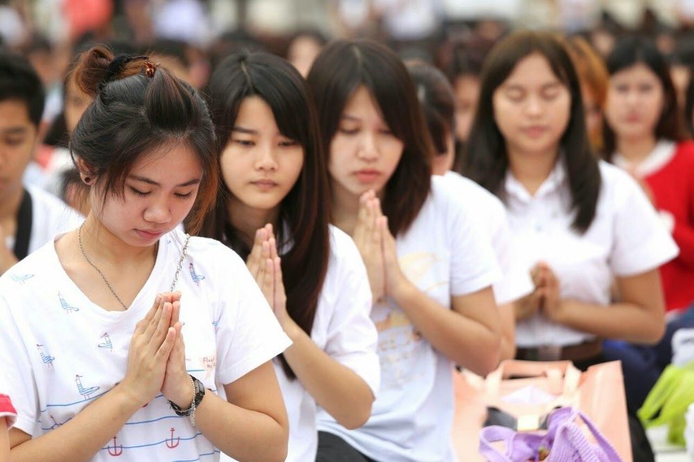 กลุ่มนักศึกษาหญิงพนมมือด้วยความสงบในพิธีตักบาตรครบรอบ 71 ปี มหาวิทยาลัยศิลปากร
