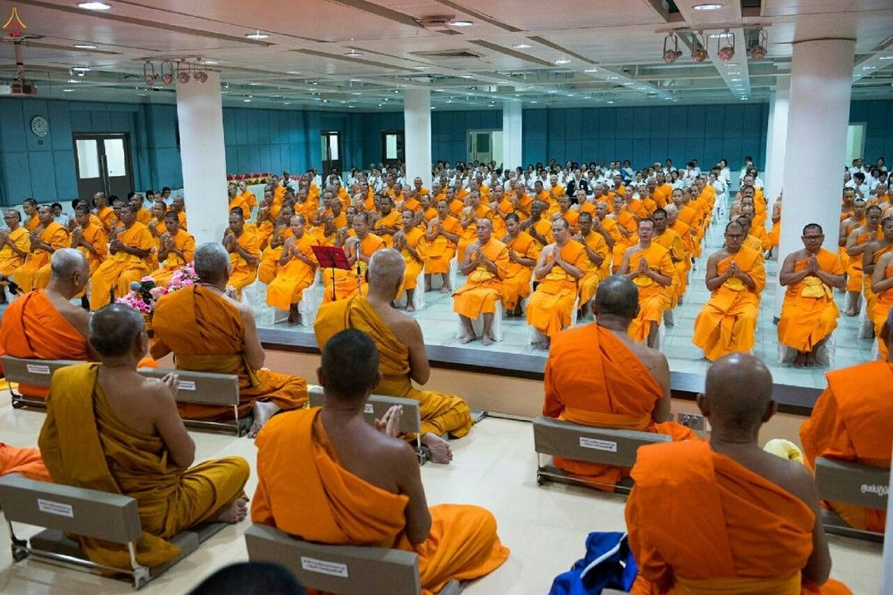 พระภิกษุสงฆ์จำนวนมากนั่งพนมมือร่วมพิธีอนุโมทนาขอบคุณคณะสงฆ์ในหอประชุม