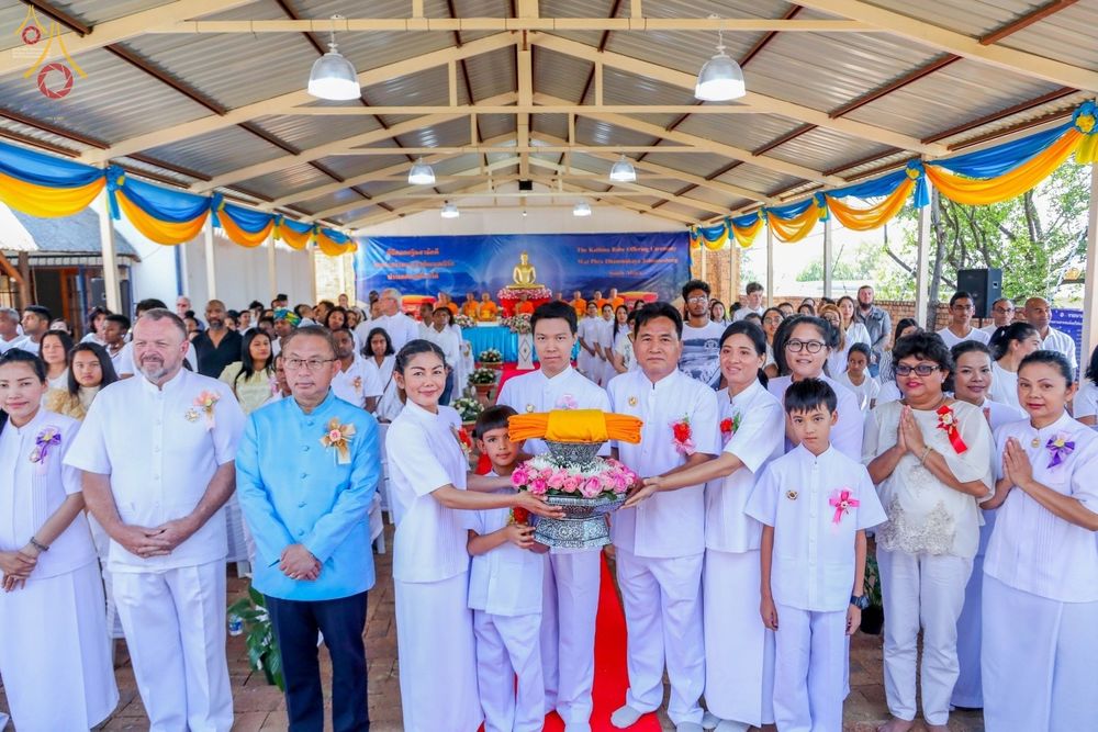 กลุ่มพุทธศาสนิกชนในชุดขาวร่วมพิธีทอดกฐินสามัคคีและถือพานผ้าไตรกฐินภายในอุโบสถวัดพระธรรมกายโจฮันเนสเบิร์ก