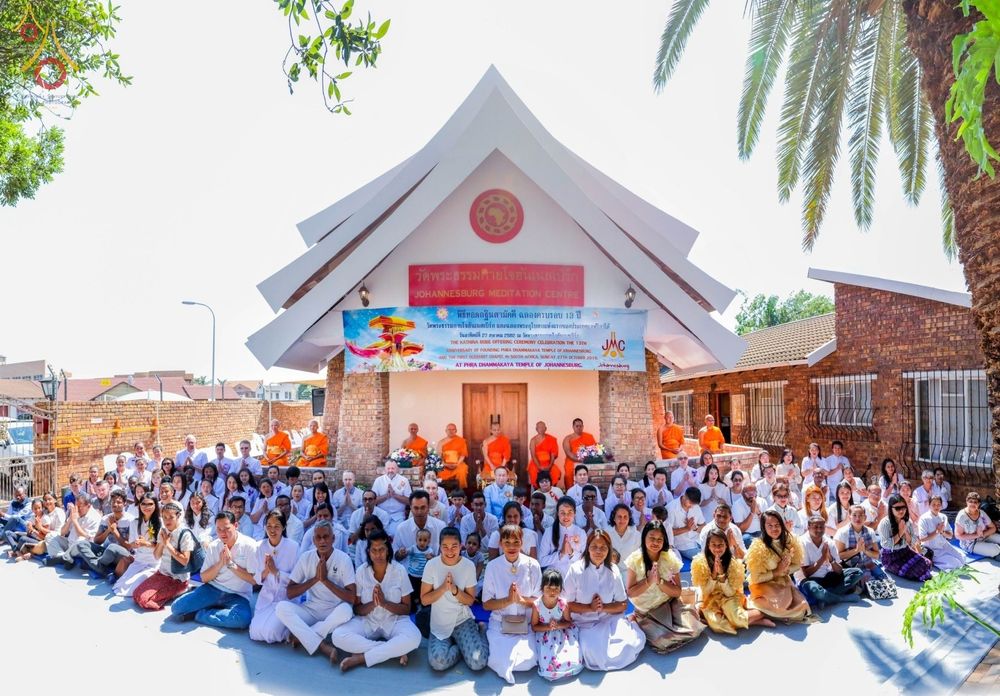 คณะสงฆ์และพุทธศาสนิกชนจำนวนมากนั่งรวมกลุ่มถ่ายภาพหน้าอุโบสถวัดพระธรรมกายโจฮันเนสเบิร์ก ประเทศแอฟริกาใต้ ในงานพิธีฉลองอุโบสถและทอดกฐินสามัคคี