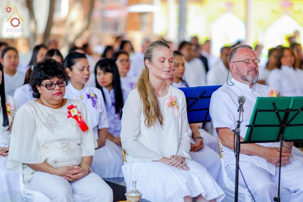 กลุ่มสาธุชนชายหญิงสวมชุดขาวนั่งหลับตาทำสมาธิในพิธีฉลองอุโบสถวัดพระธรรมกายโจฮันเนสเบิร์ก