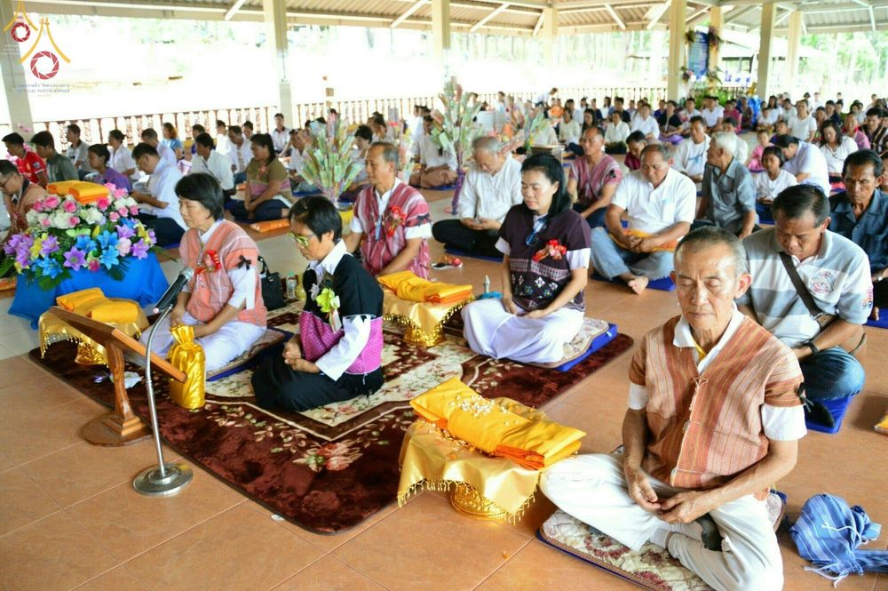 กลุ่มพุทธศาสนิกชนแต่งกายชุดพื้นเมืองนั่งบนอาสนะร่วมพิธีทอดกฐินสามัคคีภายในศาลาวัดทุ่งเจริญธรรม