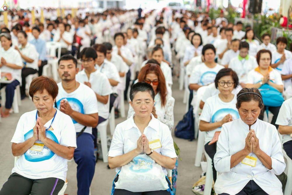 กลุ่มพุทธศาสนิกชนสวมชุดขาวนั่งพนมมือทำสมาธิในพิธีหล่อเทียนพรรษามหามงคล